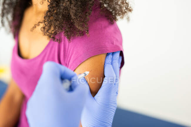 Unerkannte Ärztin in Schutzuniform und Latexhandschuhen, die anonyme afroamerikanische Patientin in der Klinik während des Coronavirus-Ausbruchs impft — Stockfoto