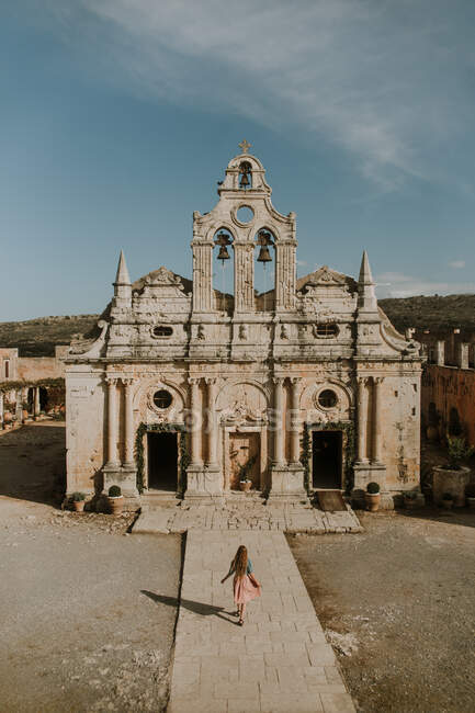 Невпізнавана жінка, що мандрувала в напрямку історичного монастиря Аркаді в стилі бароко, розташованого на Криті в сонячну погоду. — стокове фото