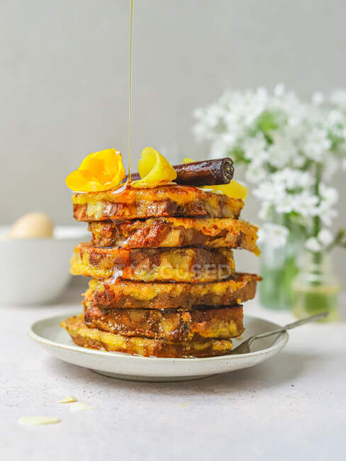 Pile of sweet French toasts being poured with honey served on plate for breakfast in kitchen — Stock Photo