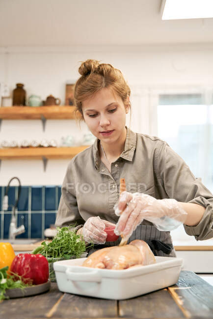 Femmina con pennello da pasticceria ingrassare pollame crudo con salsa di soia durante la cottura a casa — Foto stock
