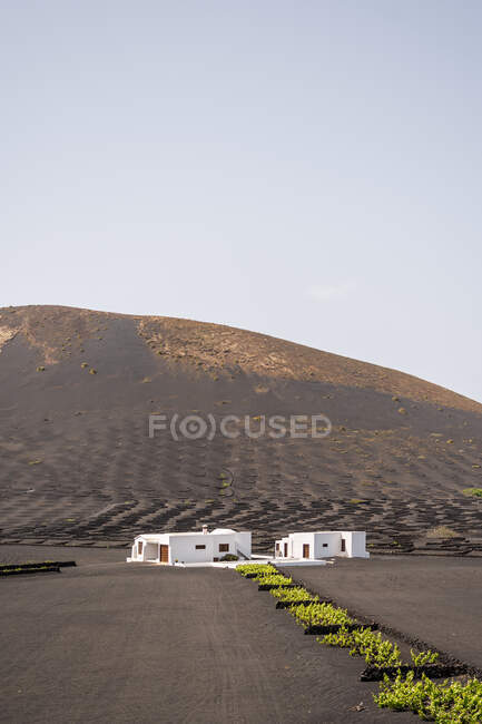 Modern white residential house located in middle of black lands against hills in haze — Stock Photo