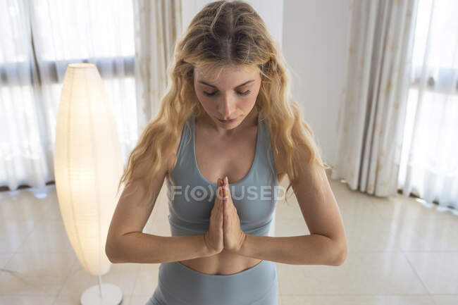 Calma fina fêmea em pé no tapete em Padmasana e meditando enquanto pratica ioga em casa — Fotografia de Stock
