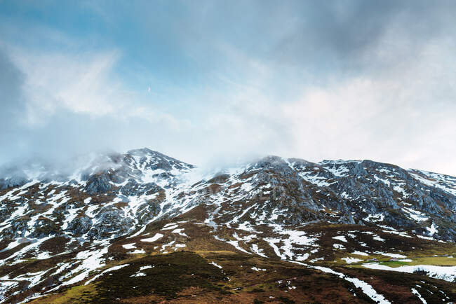 Campi verdi pittoreschi con neve in valle di Cime dell'Europa sotto cielo nuvoloso pesante in Spagna — Foto stock