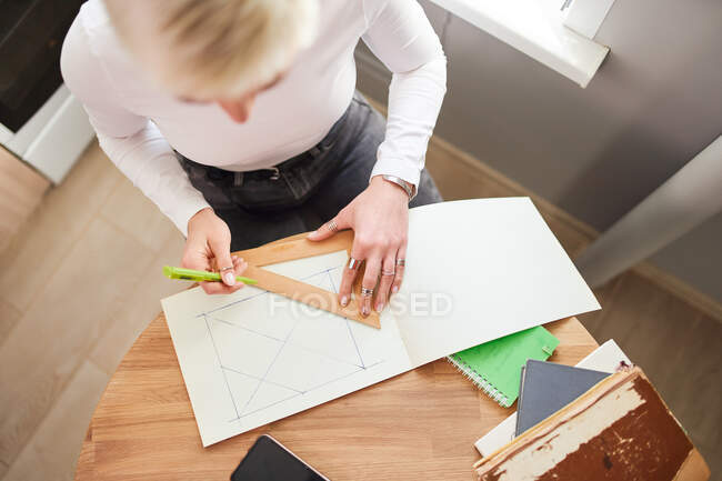 From above of crop unrecognizable female astrologist drawing on paper with triangle and pen at table — Stock Photo