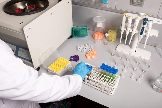 De cima de cultura cientista irreconhecível com tubos de amostra em rack contra máquina centrífuga em laboratório de cannabis — Fotografia de Stock