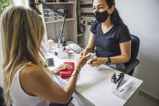 Side view of unrecognizable female customer paying to ethnic master after manicure in nail salon — Foto stock