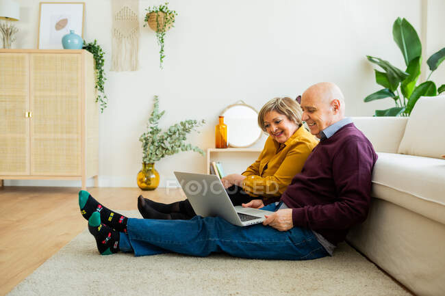 Fröhlich reifes Paar spricht auf Video-Chat auf Laptop im Wohnzimmer — Stockfoto