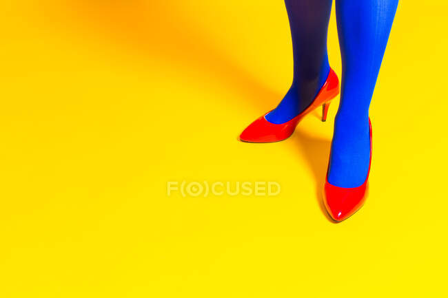 Dall'alto del raccolto irriconoscibile modello femminile indossando scarpe luminose e collant in studio vivido — Foto stock
