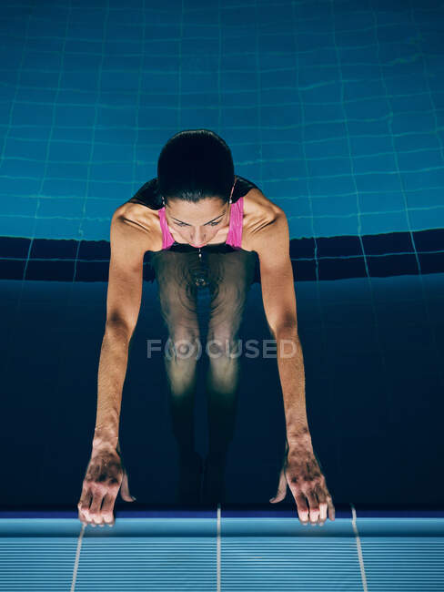 Von oben sieht man junge Athletinnen, die im Schwimmbad mit transparentem Aqua trainieren, während sie nach vorne schauen — Stockfoto