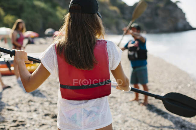 Anonyme Menschen in Schwimmwesten stehen am sandigen Meeresufer und üben mit Paddeln vor dem Kajakfahren in Malaga Spanien — Stockfoto