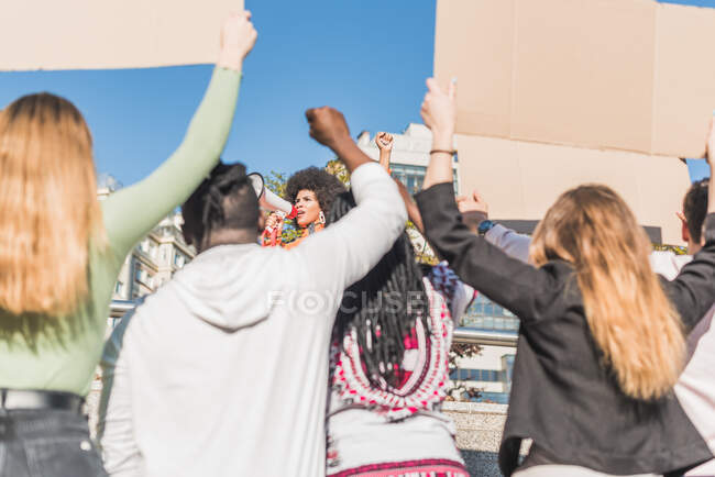 African American female social justice warrior with speaker against crop anonymous multiracial people with placards fighting for human rights in town — Foto stock