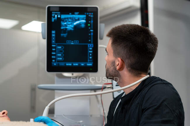 Male doctor checking up chest of woman on monitor of ultrasound machine in hospital — Stock Photo