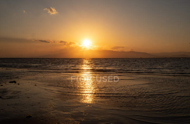 Спокійний морський пейзаж на піщаному пляжі біля спокійного моря під час заходу сонця — стокове фото