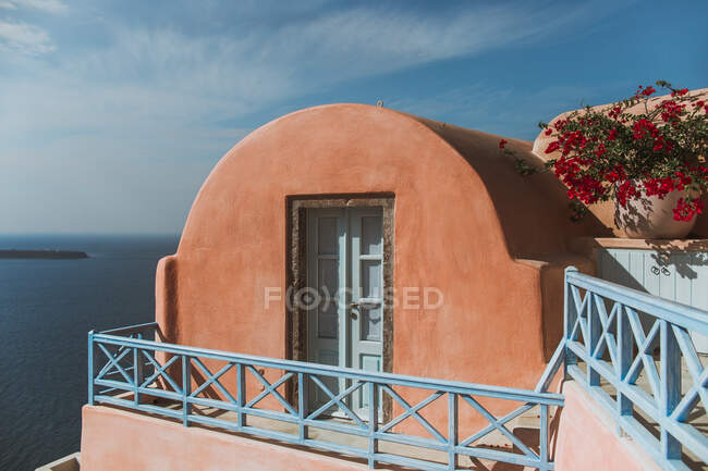 Внешний вид каменного дома с овальной крышей, расположенного на берегу моря в солнечный день в Oia Village на Санторини, Греция — стоковое фото