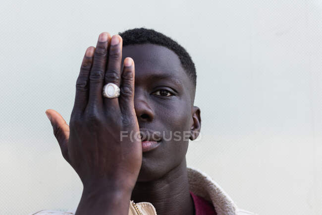 Handsome African American Male Covering Half Of Face With Hand And Looking At Camera On White Background Complexion Gaze Stock Photo