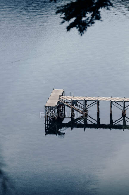 From above of shabby wooden quay located near calm pond with reflection of trees — Stock Photo