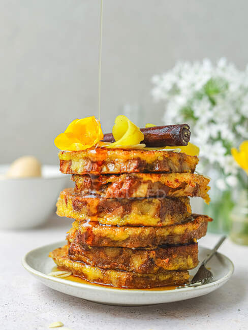 Un mucchio di toast dolci alla francese che vengono versati con miele servito sul piatto per colazione in cucina — Foto stock