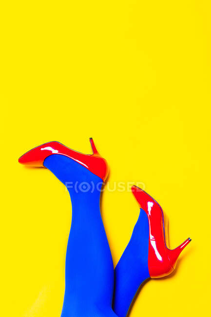 From above of crop unrecognizable female model wearing bright shoes and pantyhose in vivid studio — Stock Photo