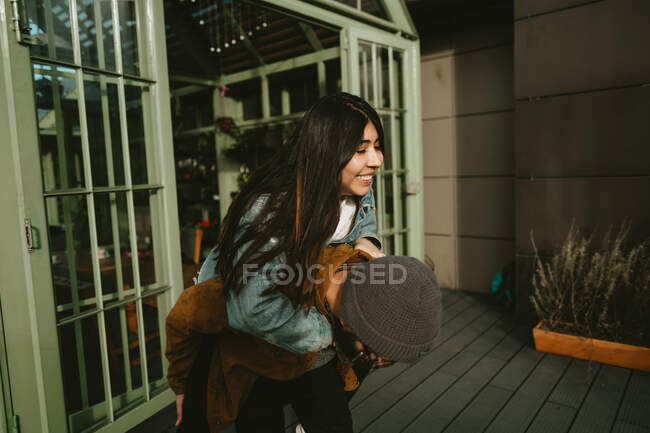 Bärtiger Freund huckepack glückliche Freundin, während Spaß auf der Terrasse an sonnigen Tag — Stockfoto