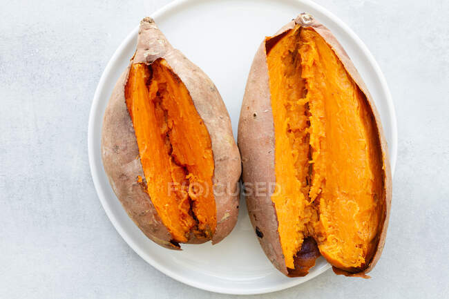 Von oben appetitliche frisch gebackene Süßkartoffeln auf weißer Keramik-Untertasse auf dem Tisch — Stockfoto