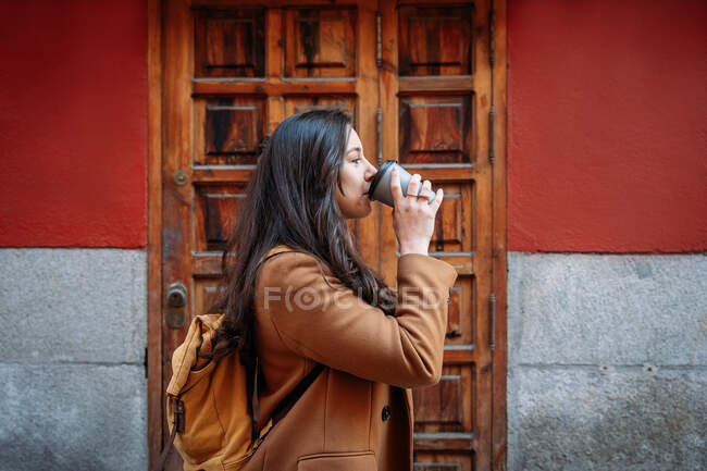 На задньому фоні жінки в пальто з гарячим напоєм. — стокове фото