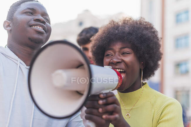 Африканский американец в женском кричит в мегафоне, протестуя против расовой дискриминации во время демонстрации черной жизни имеет значение — стоковое фото