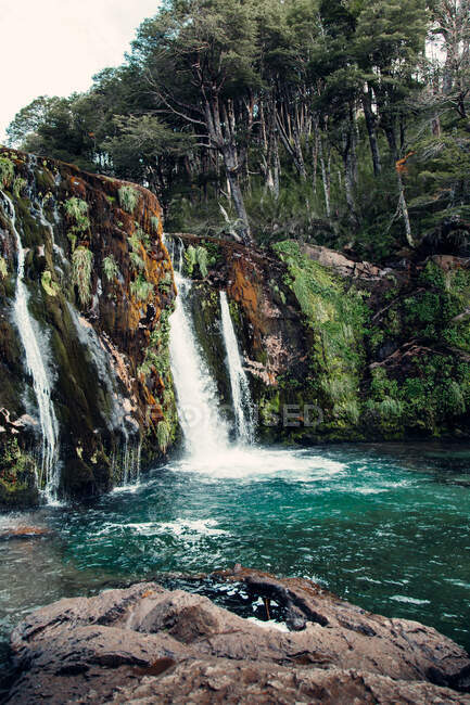 Spettacolare vista del potente torrente di cascata che scorre nel lago nella foresta montuosa — Foto stock