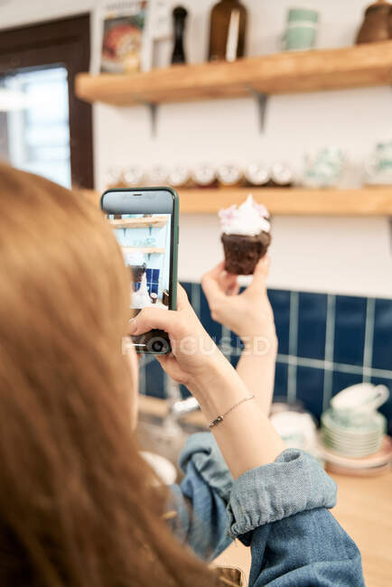 Colheita fêmea anônima tirando foto cupcake com açúcar polvilha em casa — Fotografia de Stock
