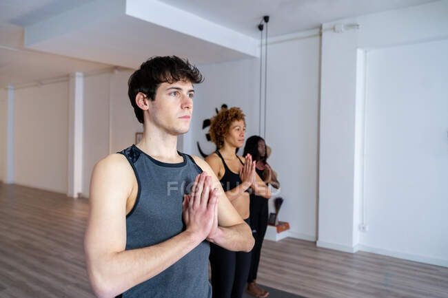 Gelassener Mann in Sportbekleidung, der mit Gebetshänden im Berg steht und während des Kurses im Studio Yoga macht — Stockfoto