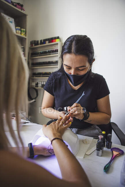 Manicurist doing nail art for female client in beauty salon in daylight — Stock Photo