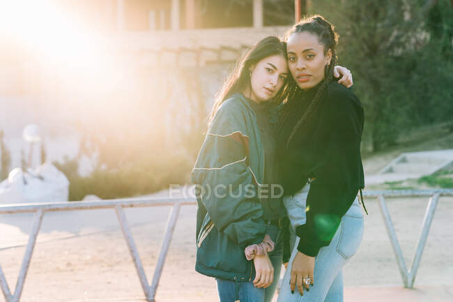 Diverse lesbische Freundinnen in trendiger Kleidung umarmen und auf dem Laufsteg in die Kamera schauen — Stockfoto