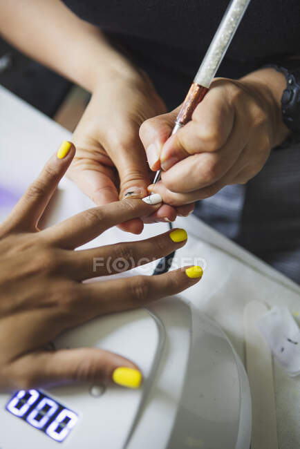 From above of crop unrecognizable manicurist doing nail art for female client in beauty salon in daylight — Stock Photo