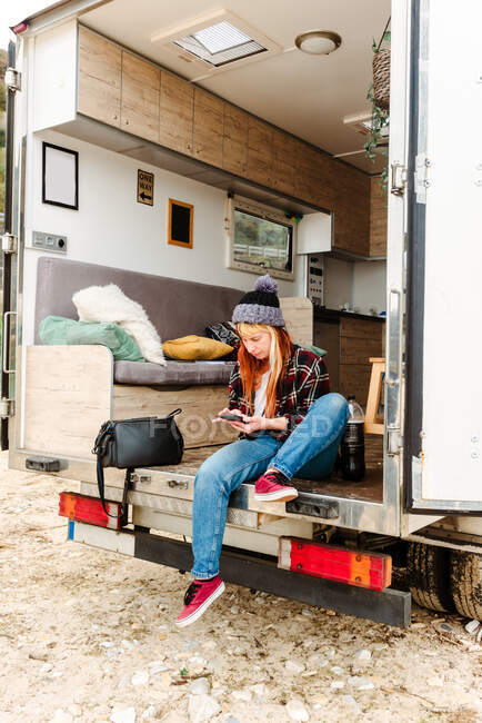 Traveling female sitting in truck and messaging on mobile phone — Stock Photo