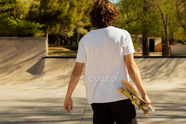 Чоловік на спині тримає скейтборд — стокове фото