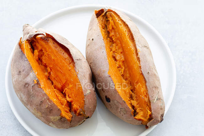 Do acima mencionado apetitoso batatas doces assadas na hora colocadas no pires de cerâmica branca na mesa — Fotografia de Stock