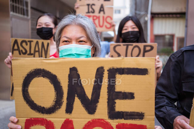Ethnic activists with I Am Not A Virus and One Race inscriptions on placards during Stop Asian Hate movement in town — Stock Photo