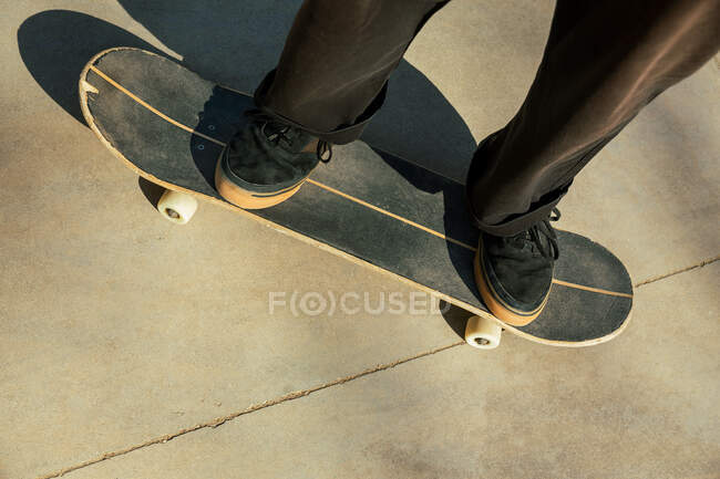 Primo piano dei piedi di un giovane che cavalca uno skateboard per strada — Foto stock