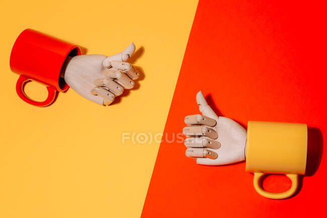 Творческая декоративная деревянная рука с большими пальцами вверх внутри красочные кружки на желтом и красном фоне в студии — стоковое фото