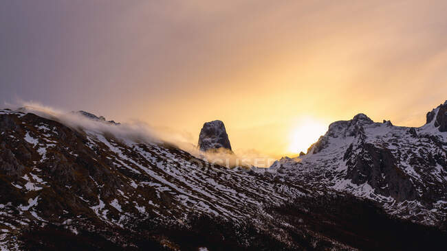 Paysage grand angle des pics d'Europe gamme avec de la neige et du brouillard sous les nuages pendant le coucher du soleil — Photo de stock