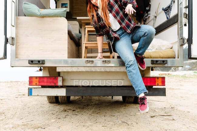 Crop female hipster getting out of truck parked at seaside during summer travel — Stock Photo