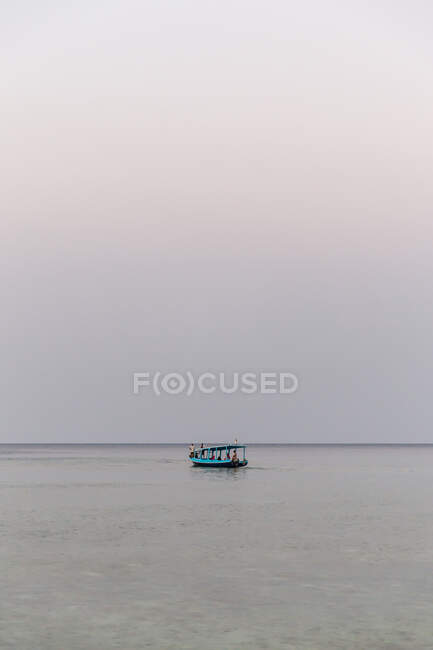 Pequeno barco de pesca ancorado na água do mar azul-turquesa sob céu nublado no crepúsculo pacífico — Fotografia de Stock