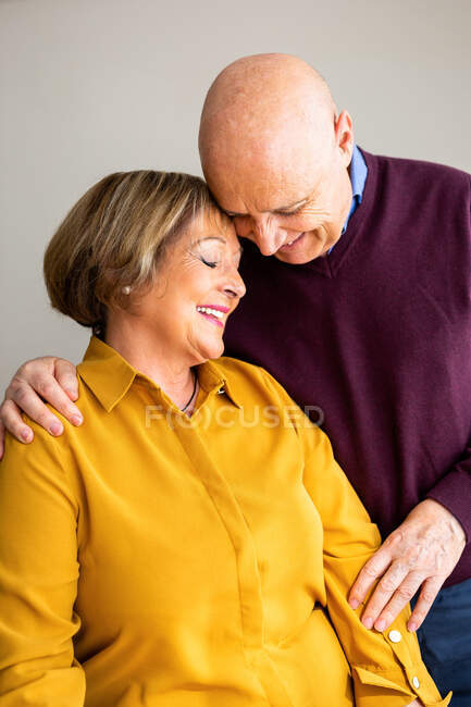 Cheerful middle aged couple embracing at home while spending time together and enjoying weekend — Stock Photo
