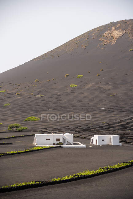 Modern white residential house located in middle of black lands against hills in haze — Stock Photo