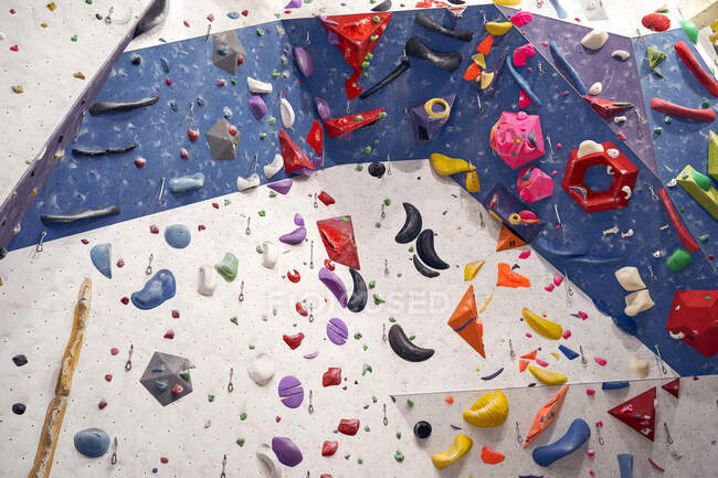 Снизу искусственной стены с красочными рукоятками, расположенными в современном альпинистском центре — стоковое фото