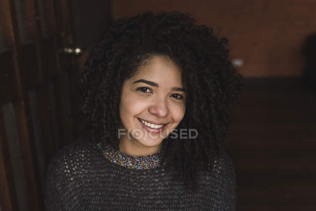 From above delighted ethnic female with Afro hairstyle while looking at camera - foto de stock