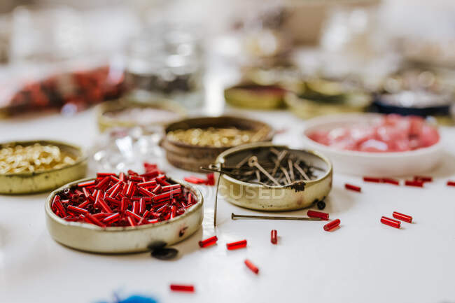 Vista laterale di varie perle decorative tromba in contenitori di metallo su tavolo di legno — Foto stock