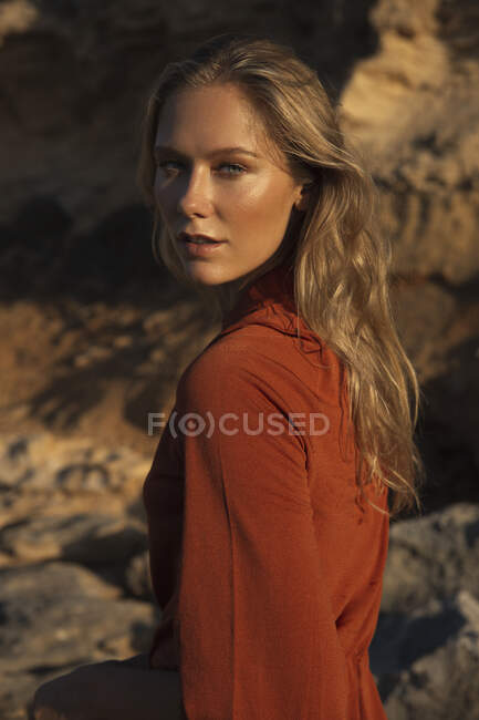 Retrato de pacífica jovem mulher em pé na encosta de pedra áspera e olhando para a câmera — Fotografia de Stock