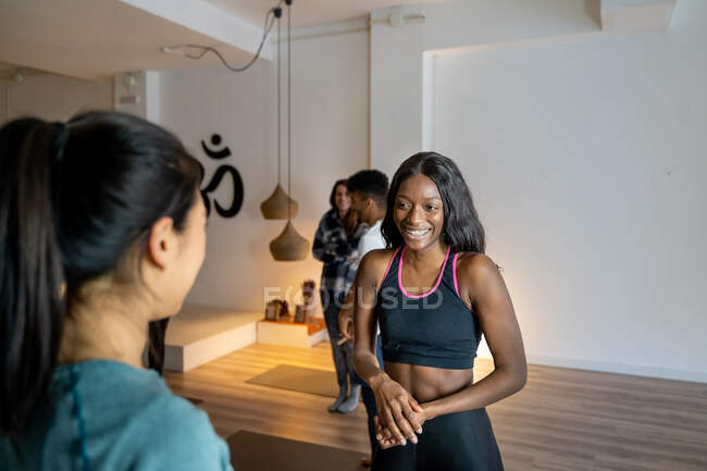 Filles multiraciales gaies en vêtements de sport debout dans un studio de yoga et de parler entre eux après les cours — Photo de stock
