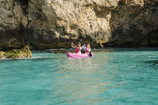 Мандрівники, що плавають на бірюзовій морській воді біля скелястого берега в сонячний день у Малазі (Іспанія). — стокове фото