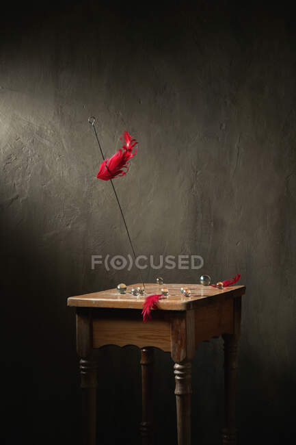 Decoration on metal stick on wooden retro stool with small crystal balls and feathers on gray background — Stock Photo